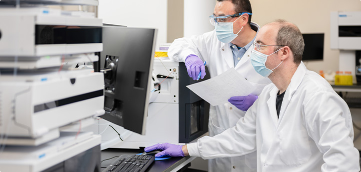 Two lab workers reviewing test results on a computer.